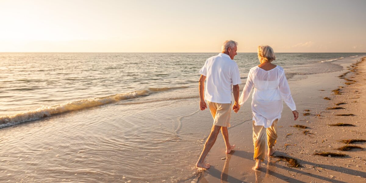 happy old senior man and woman walking on beach