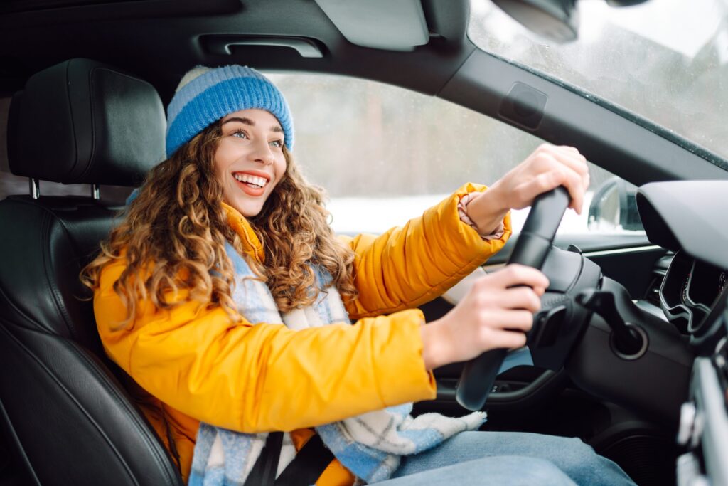 happy woman in winter outfit driving car