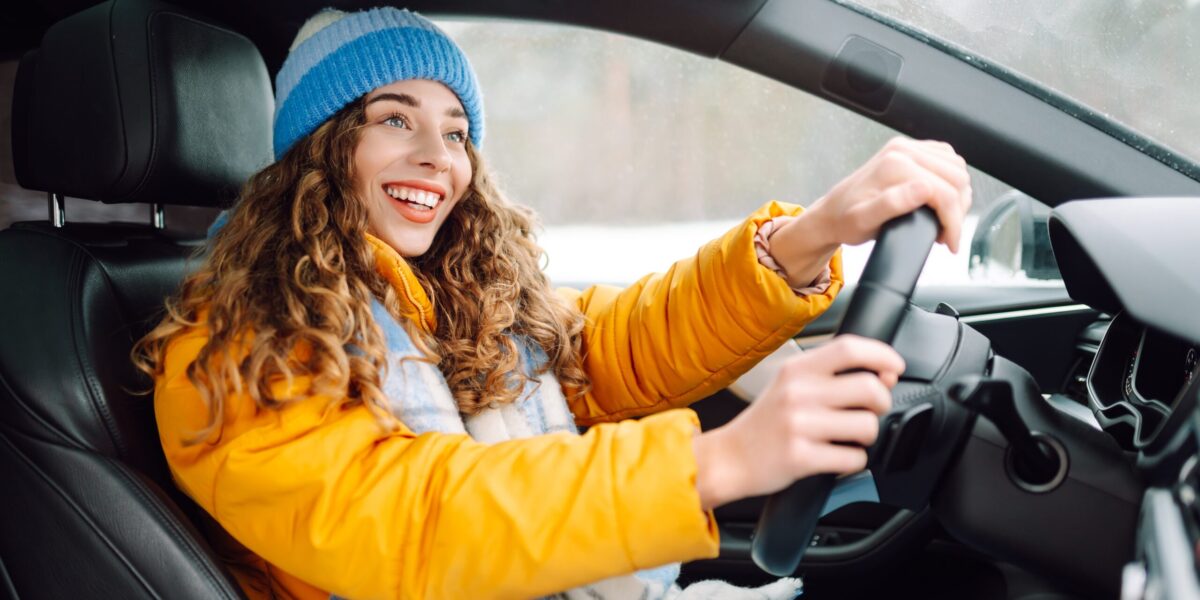 happy woman in winter outfit driving car