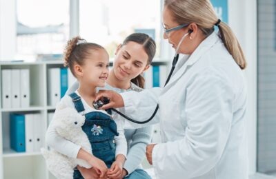 child and mother at exam with doctor using stethescope