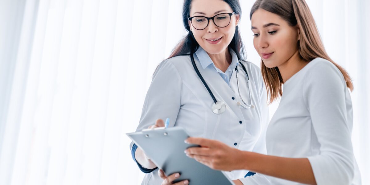 woman doctor and her female patient looking at clipboard