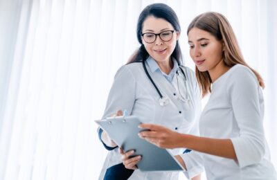 woman doctor and her female patient looking at clipboard