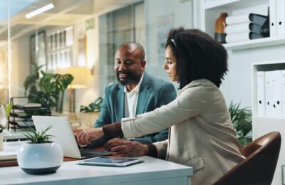 two people sitting at desk on laptop