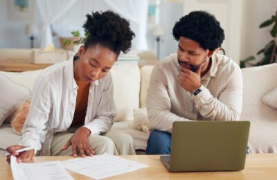 couple on sofa reviewing documents and laptop